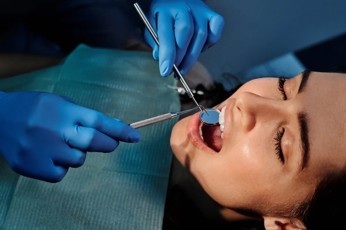 Patient smiling while looking at her teeth in a hand mirror.